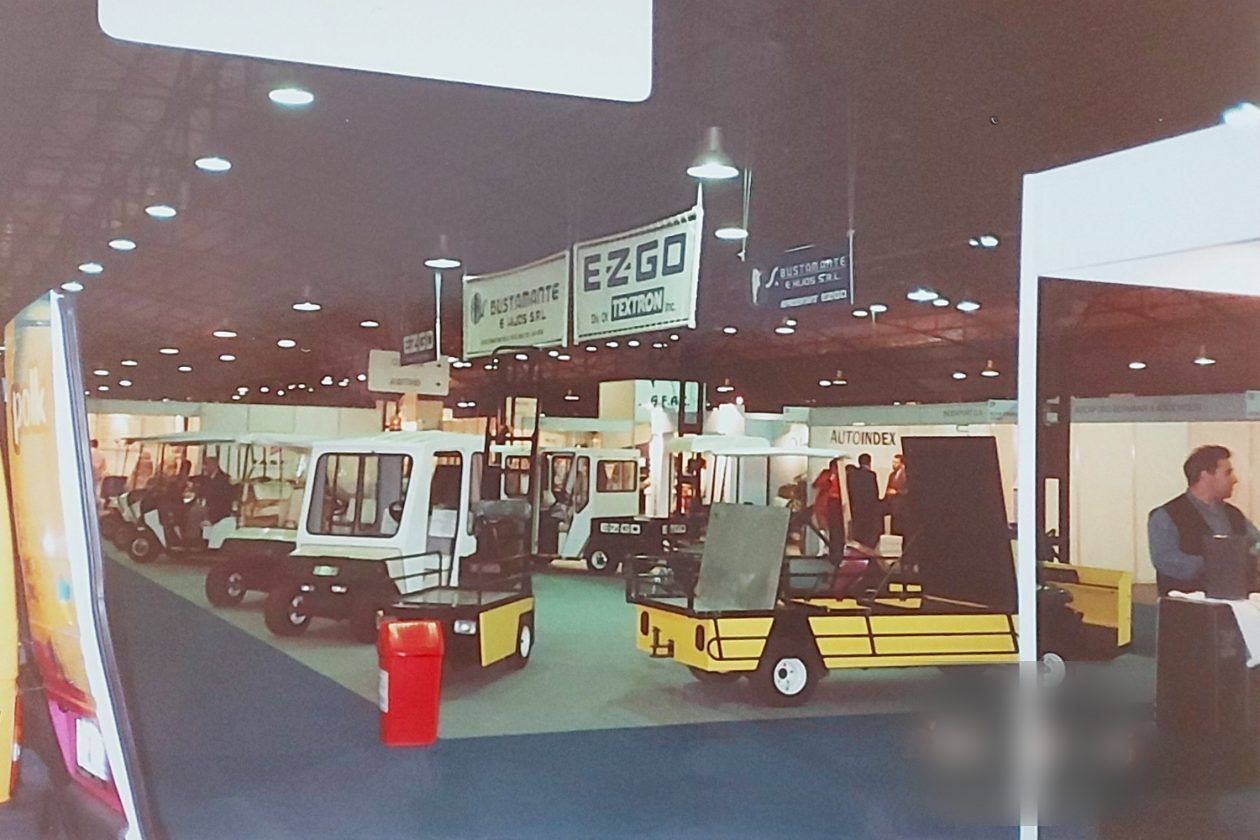 Stand de E-Z-GO y S. Bustamante e Hijos con vehículos utilitarios en feria cubierta, 1996
