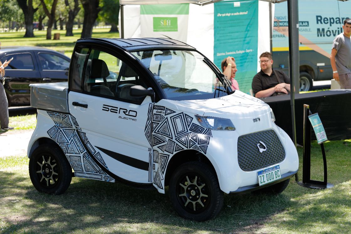 Utilitario Sero Electric blanco con diseño gráfico en un stand al aire libre